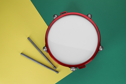 Children's drum with drumsticks on color background, top view