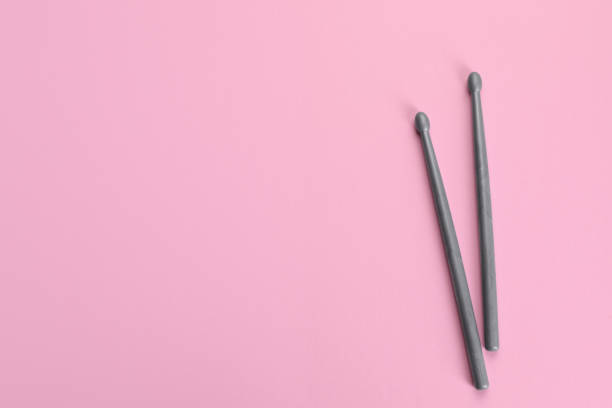 istock Two grey drumsticks on pink background, top view. Space for text 1865574089