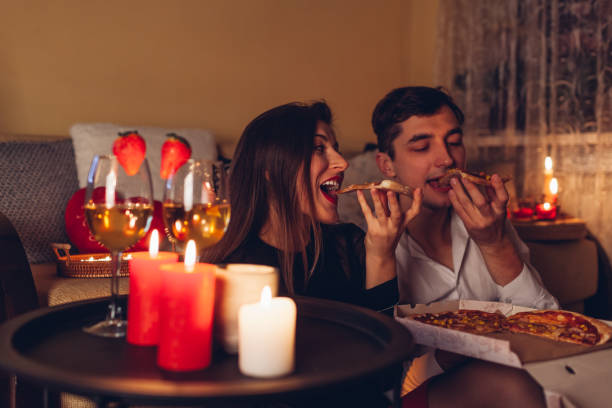istock Valentines Day couple in love eating pizza drinking wine with strawberries having romantic dinner celebrating at home 1865576701