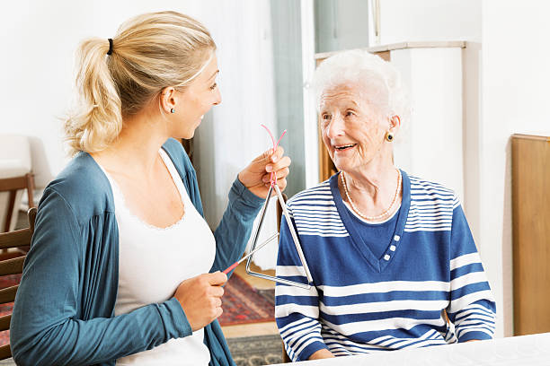 Alzheimer therapy senior woman musical instrument young therapist playing a triangle to senior woman, music therapy , useful especially for people with Alzheimer disease triangle percussion instrument stock pictures, royalty-free photos & images