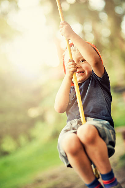 Little boy zipping on zip line in outdoors amusement park.