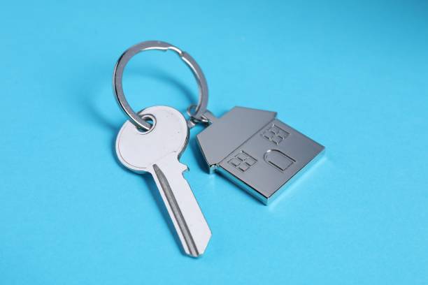 istock Key with keychain in shape of house on light blue background, closeup 1865584502