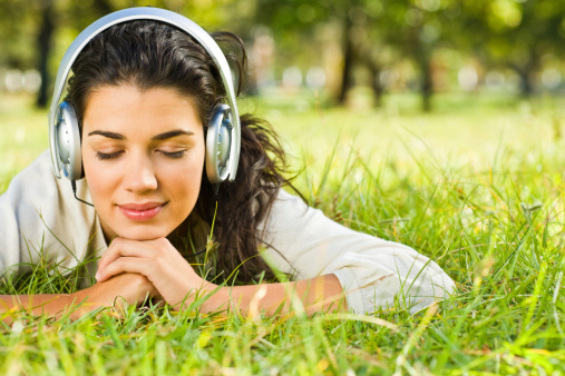 Smiling young woman listening to music at park