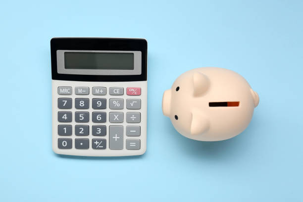 istock Calculator and piggy bank on light blue background, top view 1865586437