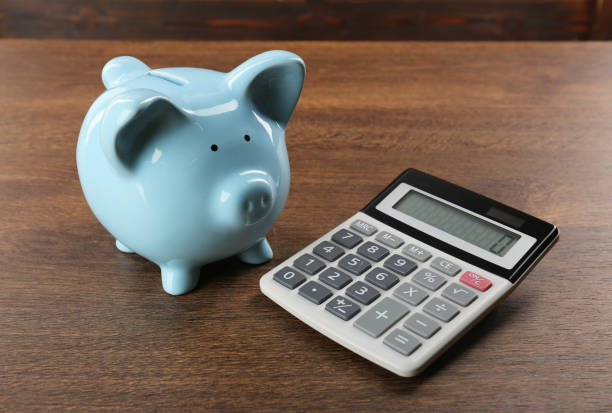 istock Calculator and piggy bank on wooden table 1865588235