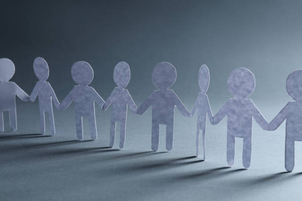 istock Teamwork concept. Paper figures of people holding hands on grey background, closeup 1865590348