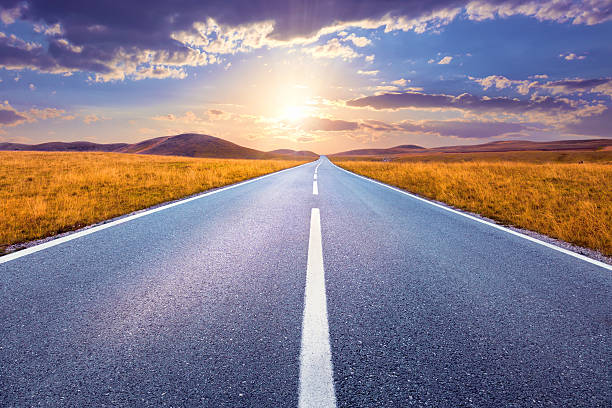 conducción en una carretera vacía en la puesta de sol - punto de fuga fotografías e imágenes de stock