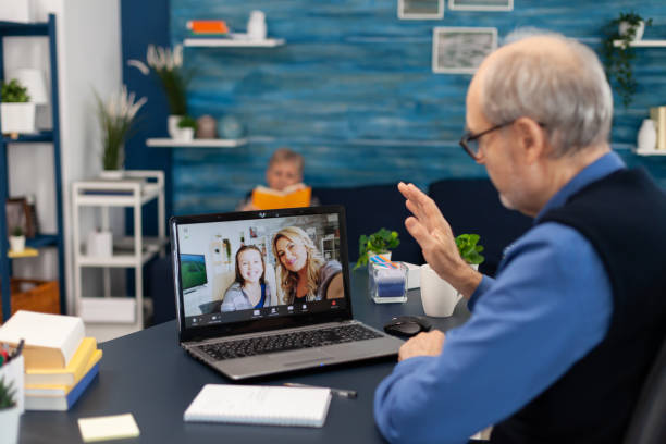istock Elderly man waving at camera during online call with family 1865621378