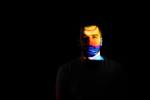 Portrait of multicolored handsome man illuminated by neon lights