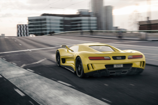 A modern yellow sports car speeding along a city street. Unique and generic sports car design.  Designed and modelled entirely by myself. Very high resolution 3D composite render. All markings are ficticious.