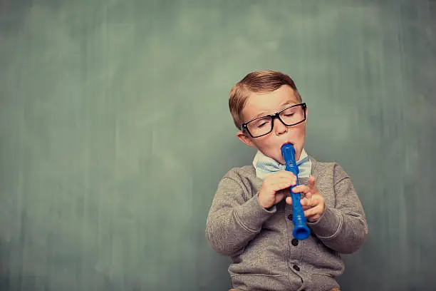 A young nerd is playing some sweet music on his recorder. 