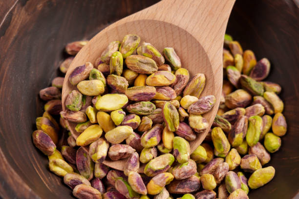 Shelled pistachio nuts in wooden spoon. Raw dried kernels