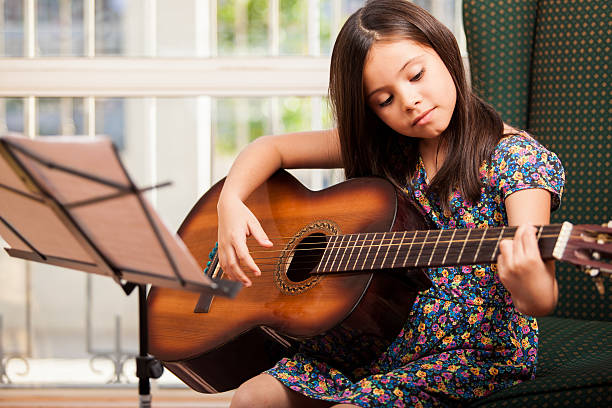 mignonne petite fille jouant de la guitare - guitar child music learning photos et images de collection