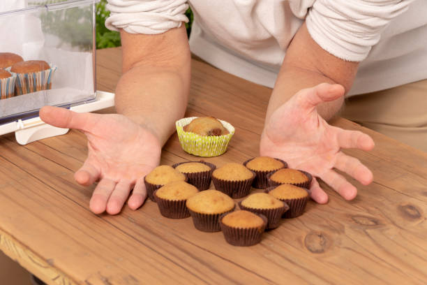 istock Shared Treat: Delicate Hands Surrounding Muffins on a Wooden Table 1865664100