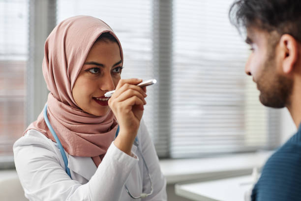 muslim female physician checking patients vision - penlight imagens e fotografias de stock