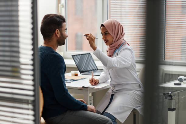 young female doctor in hijab examining patients eyesight - penlight imagens e fotografias de stock