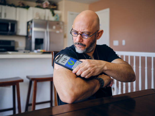 Dojrzały mężczyzna w domu sprawdzający poziom cukru we krwi – zdjęcie