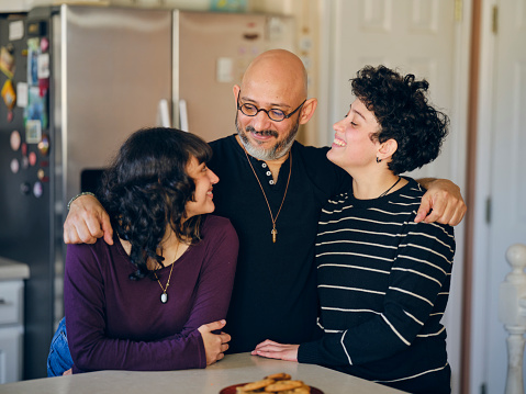 A hispanic father and daughters in a home.