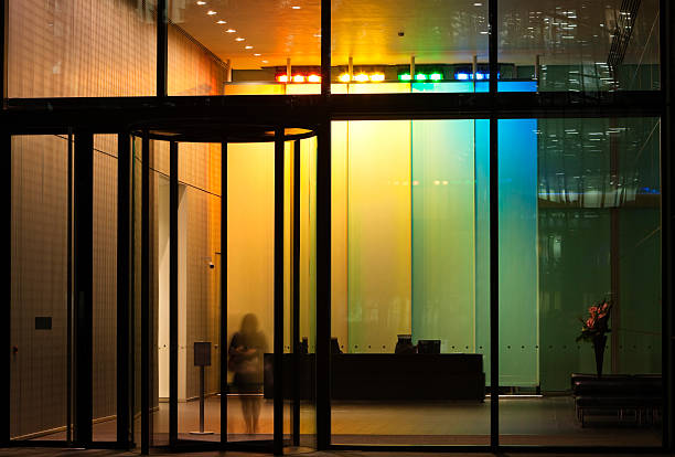 donna in carriera uscita illuminato lobby attraverso la porta girevole - architecture bright vibrant color brilliant foto e immagini stock