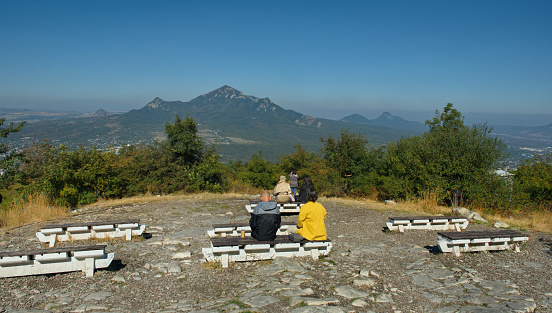 Russia, Pyatigorsk. Tourists on a wooden bench on the observation deck of Mount Mashuk overlooking the city and Mount Beshtau.