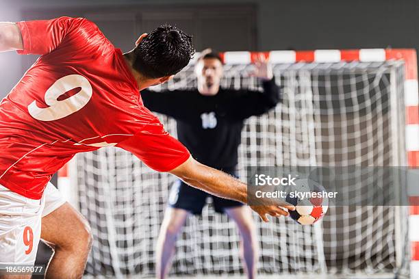 Handball Player In Red Shooting Toward A Net Stock Photo - Download Image Now - Team Handball, Court Handball, Playing
