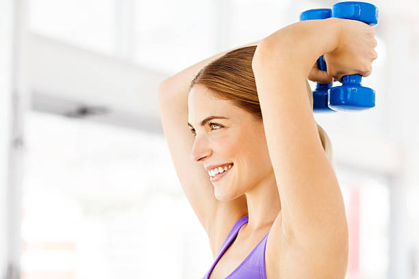 Woman Looking Away While Exercising With Dumbbells In Gym