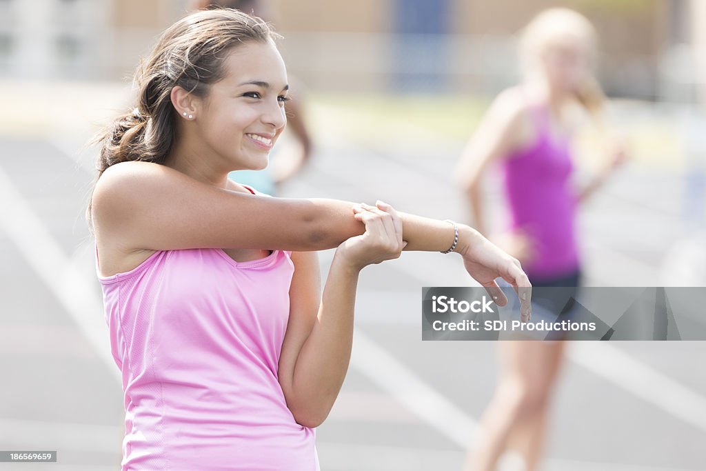 High school atleta de alongamento antes da corrida na pista evento - Foto de stock de Adolescente royalty-free