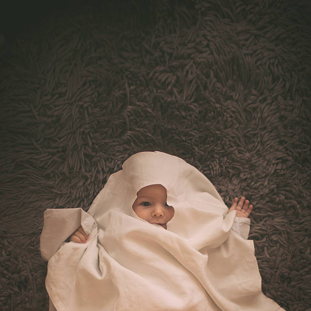 Black and white image image of a three month old baby girl smiling at the camera while laying down and wearing a tutu.