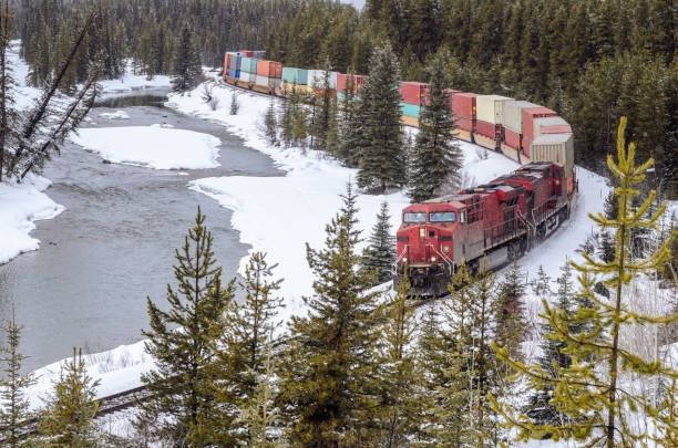 istock Cargo train running alongside a frozen river in the mountains during heavy snowfall 1865711837