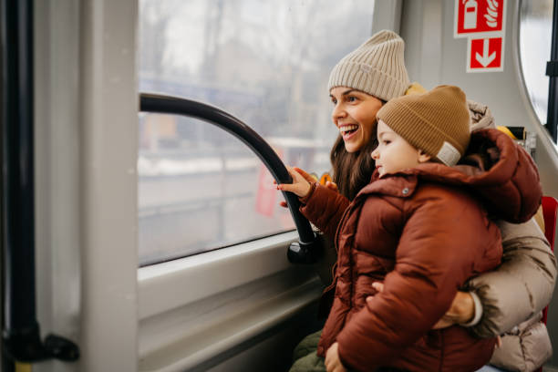 Young smiling woman with her toddler using a public transport