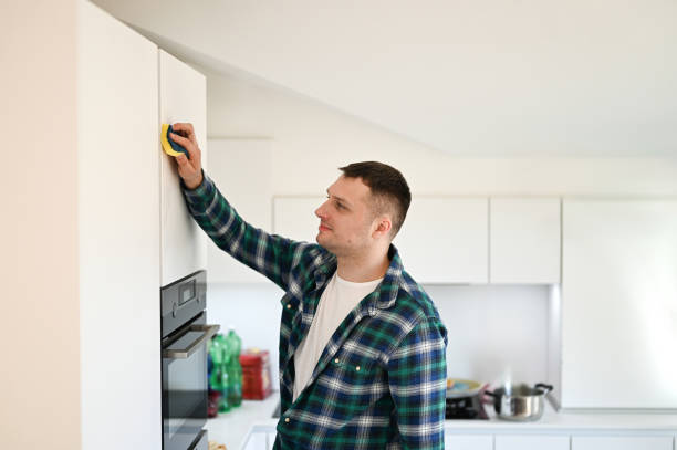 istock portrait of millennial man cleaning white modern kitchen. 1865716940
