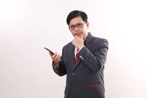 istock Confused asian businessman holding a cell phone while thinking something, Isolated on white 1865717053