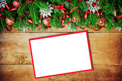 Christmas garland and empty card on wooden background