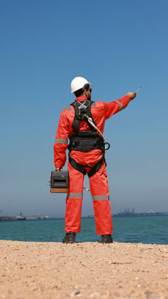 l'ingegnere con l'uniforme di sicurezza arancione e l'imbracatura di sicurezza lavorano sulla linea del sito della fabbrica - engineer environment orange manual worker foto e immagini stock