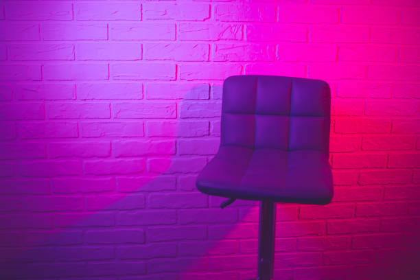istock Purple bar stool on a brick wall background in neon light 1865770499