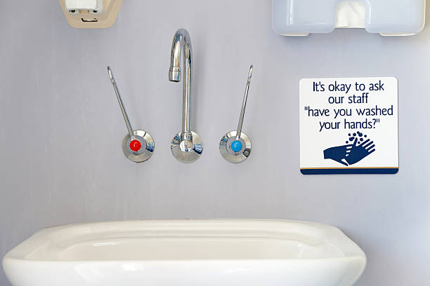 Wash your hands sign with sink, faucet, hand towel and soap dispenser in a healthcare or hospital setting.