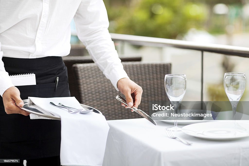 Waiter Setting The Table In Restaurant Midsection of waiter setting the table in restaurant. Horizontal shot. Setting The Table Stock Photo