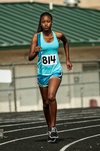 istock Young female track competitor running relay race - III 186579733