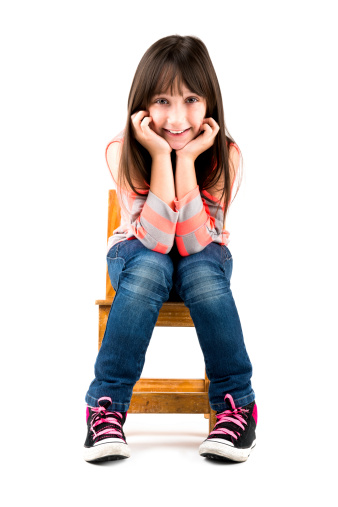 Girl sitting on a little chair isolated with clipping path.