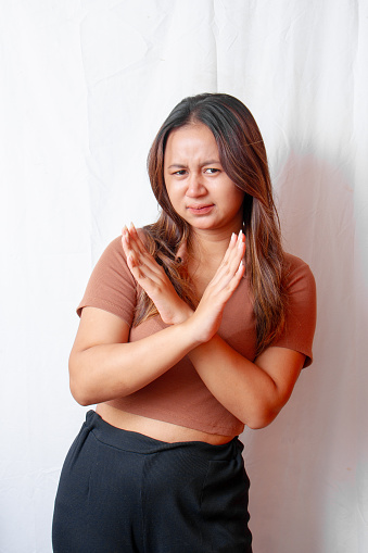 Stop. Concerned Asian woman showing rejection sign, saying no, raising awareness, standing on white background