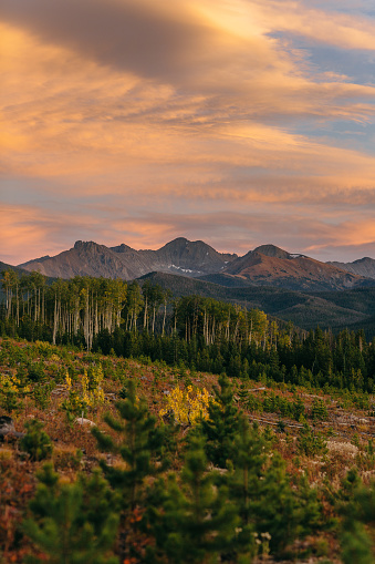 Clouds turn orange over the mountains as the sun sets in State Forest State Park in Colorado.