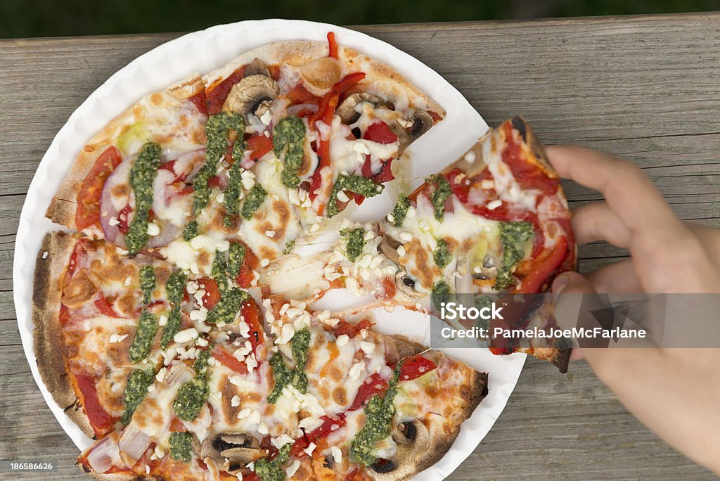 Mano tirando fetta di Pizza vegetariana di Pesto - Foto stock royalty-free di Piatto di carta