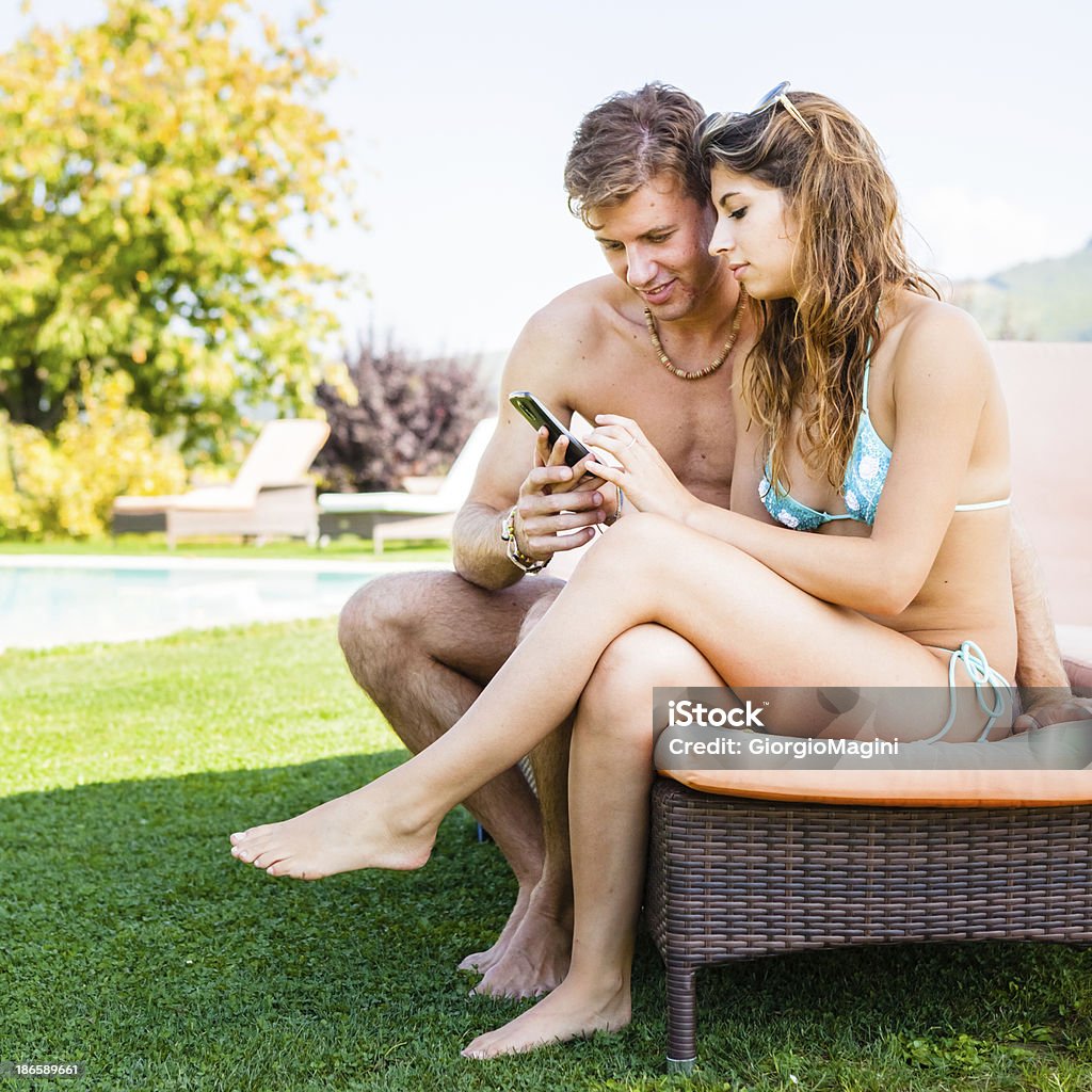 Tarde adolescentes usando Smartphone pela à beira da piscina - Foto de stock de 16-17 Anos royalty-free