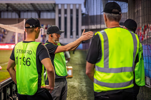 Soccer field security guards in reflective vests talking