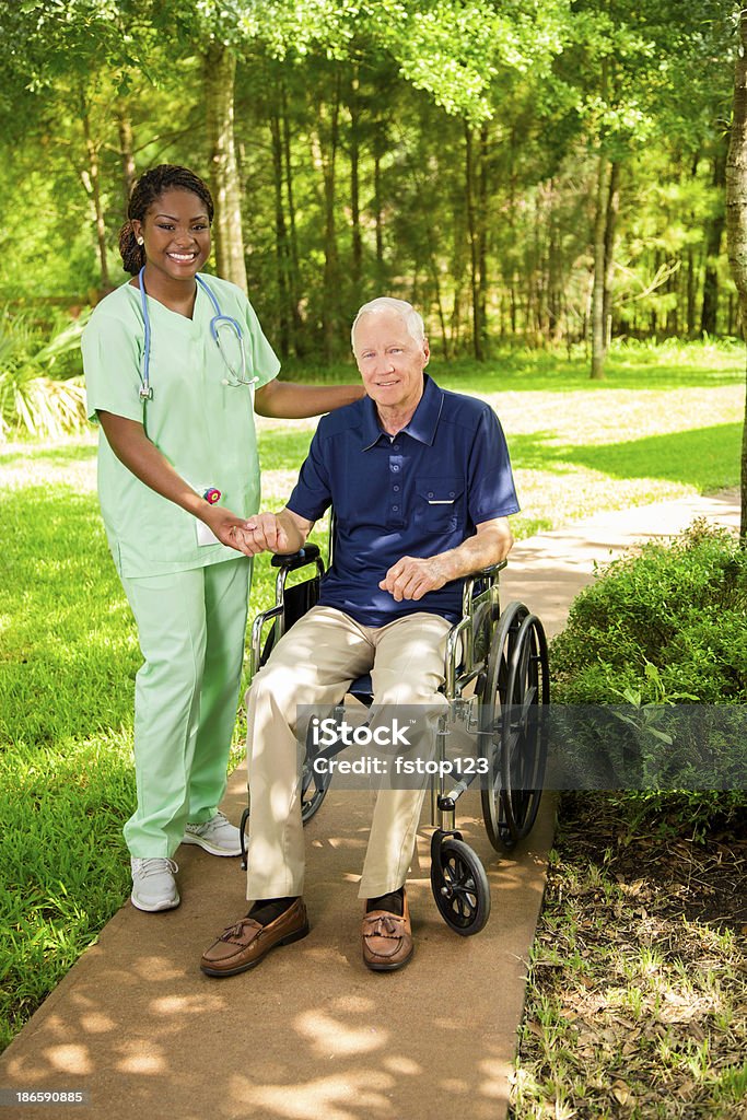 Medical:  Happy caregiver with senior man in wheelchair. Senior man visits with home health caregiver outside. 20-24 Years Stock Photo