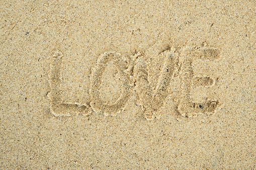 Love hand written text on sand