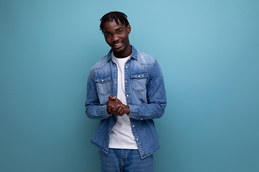 charismatic dude african man with curly hair in a denim jacket on a blue background.