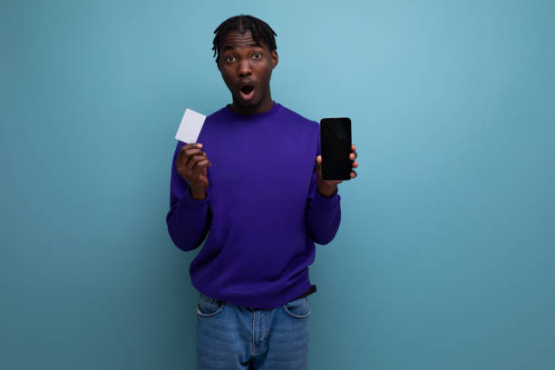 istock african young brunette man with dreadlocks makes a payment using a card and a smartphone for shopping 1865919331