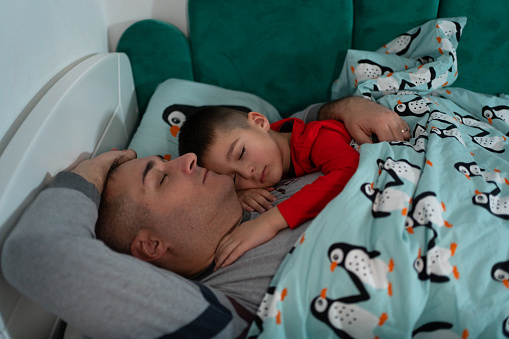 Father and son sleeping together in bed
