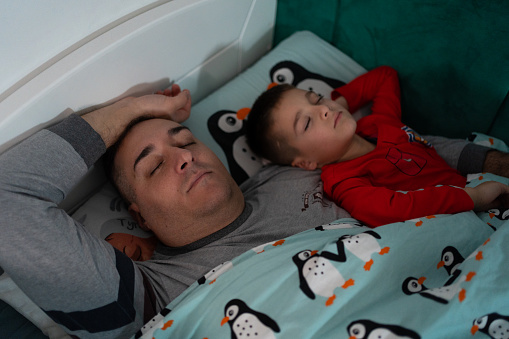 Father and son sleeping together in bed
